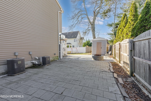 view of patio featuring a fire pit, central AC, and a storage shed