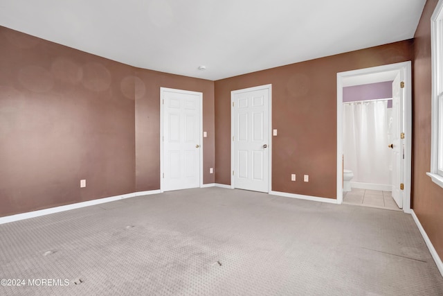 unfurnished bedroom with light colored carpet and ensuite bath