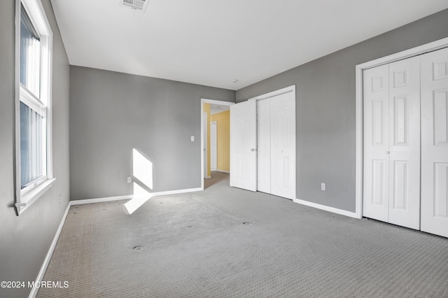 unfurnished bedroom featuring two closets and carpet floors