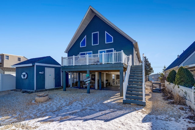 snow covered rear of property with a wooden deck and a shed