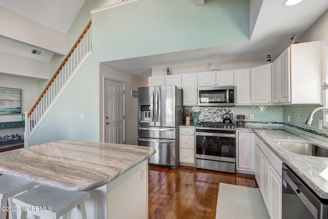 kitchen featuring a kitchen breakfast bar, appliances with stainless steel finishes, a kitchen island, white cabinets, and sink