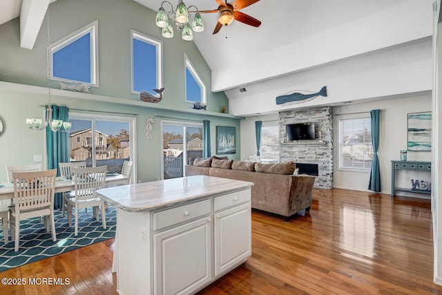 kitchen featuring hanging light fixtures, light hardwood / wood-style floors, a kitchen island, white cabinetry, and ceiling fan with notable chandelier