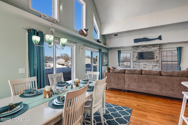 dining space with a high ceiling, hardwood / wood-style flooring, and a notable chandelier