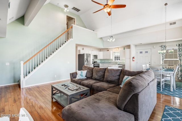 living room featuring ceiling fan with notable chandelier, high vaulted ceiling, and light wood-type flooring