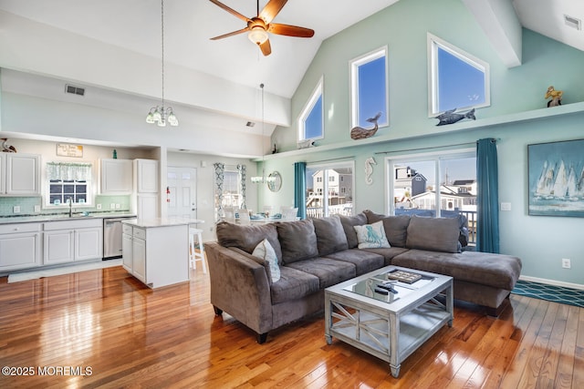 living room with high vaulted ceiling, ceiling fan, light hardwood / wood-style flooring, and sink