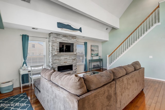 living room featuring vaulted ceiling, a fireplace, and wood-type flooring