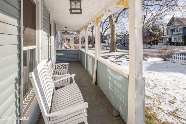 snow covered back of property featuring covered porch