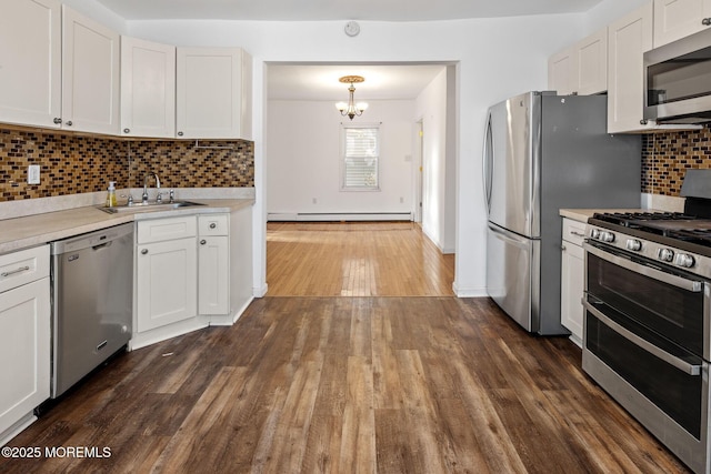 kitchen featuring stainless steel appliances, white cabinets, decorative light fixtures, and sink