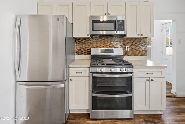 kitchen with stainless steel appliances, white cabinetry, tasteful backsplash, and dark wood-type flooring