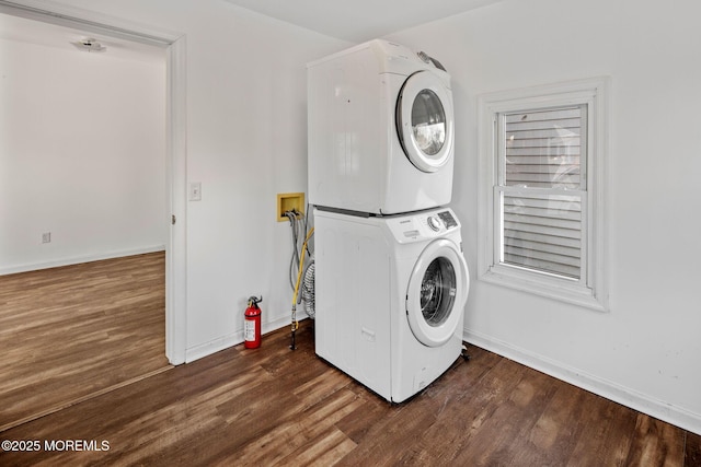 clothes washing area featuring dark hardwood / wood-style flooring and stacked washer and clothes dryer