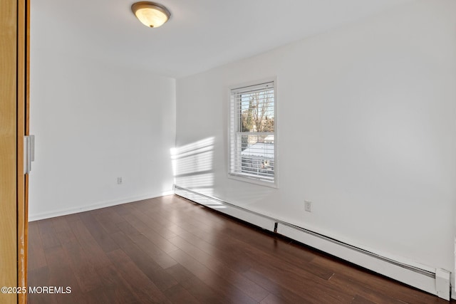 empty room featuring baseboard heating and dark wood-type flooring