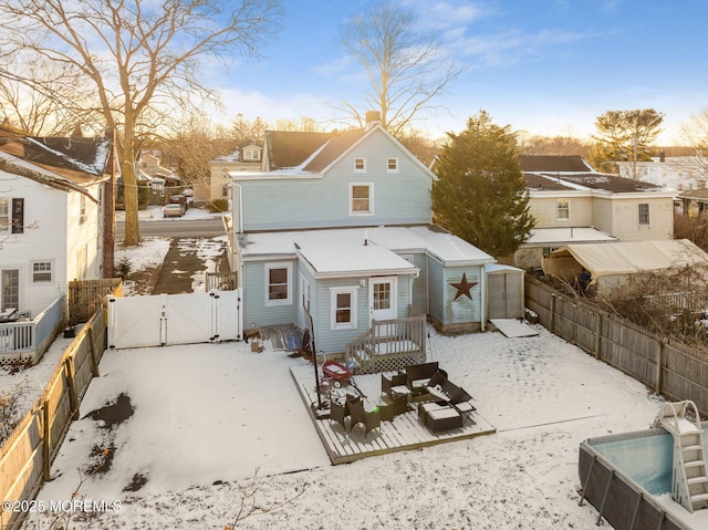 snow covered rear of property featuring a deck and a shed