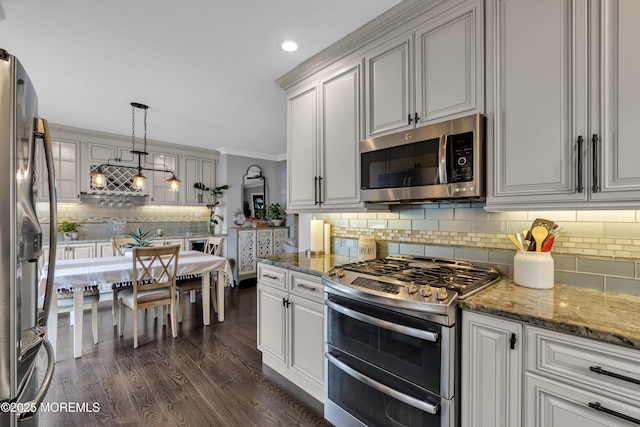 kitchen with decorative light fixtures, dark hardwood / wood-style floors, stone counters, crown molding, and appliances with stainless steel finishes