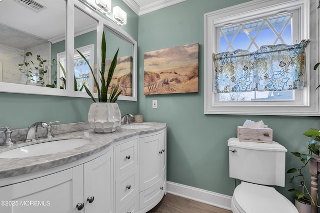 bathroom with toilet, a healthy amount of sunlight, crown molding, and vanity