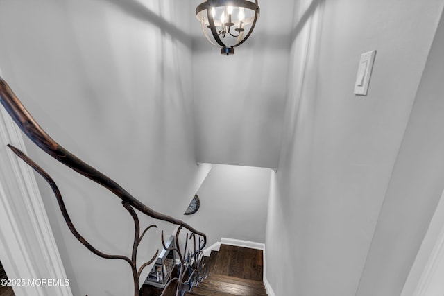 stairs featuring wood-type flooring and an inviting chandelier