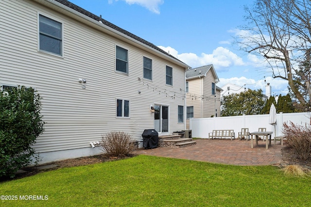 rear view of property featuring a patio area, fence, and a lawn