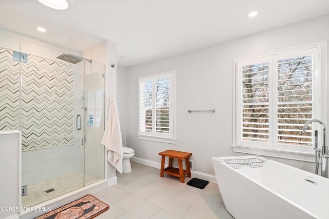 full bathroom featuring a stall shower, a freestanding tub, baseboards, and toilet