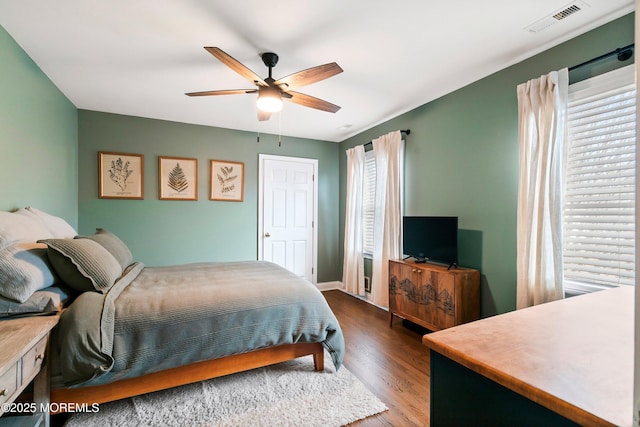 bedroom with a ceiling fan, visible vents, and wood finished floors