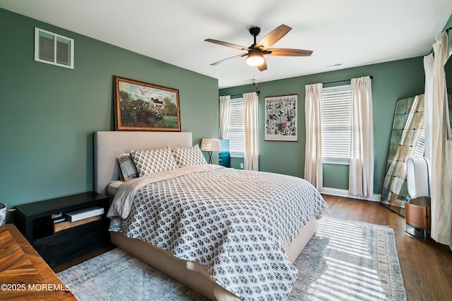 bedroom featuring a ceiling fan, baseboards, visible vents, and wood finished floors