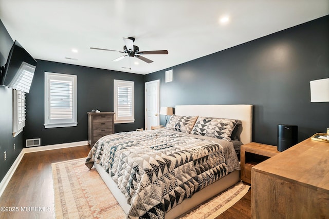 bedroom with a ceiling fan, wood finished floors, visible vents, and baseboards