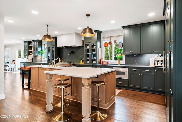 kitchen with tasteful backsplash, dark wood finished floors, a breakfast bar area, white oven, and wall chimney range hood