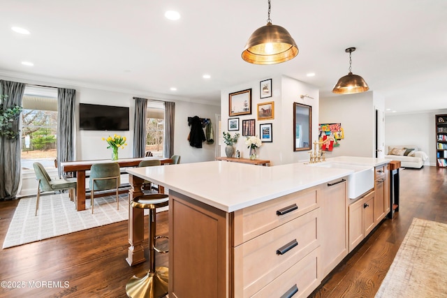 kitchen with a center island, recessed lighting, light countertops, dark wood-type flooring, and a sink