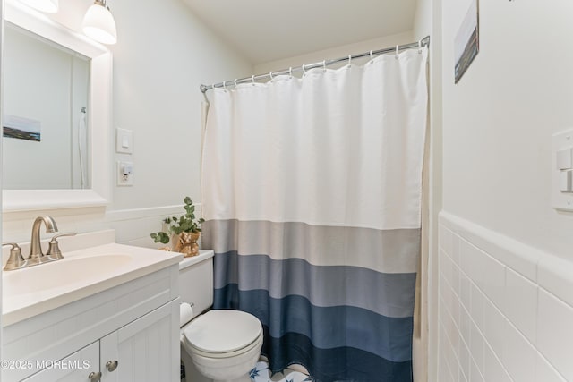 bathroom featuring tile walls, toilet, vanity, and walk in shower