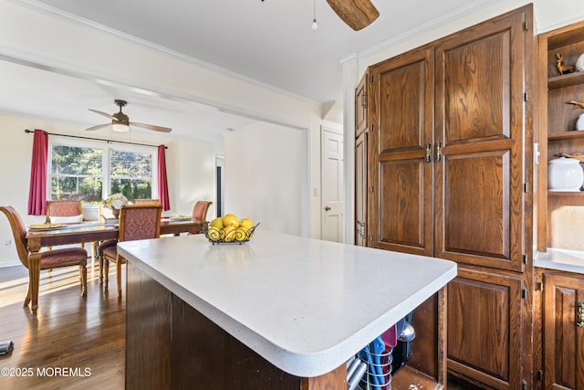 kitchen with ceiling fan, dark hardwood / wood-style floors, a center island, and crown molding