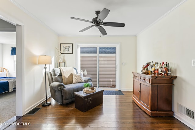 sitting room with ceiling fan, dark hardwood / wood-style flooring, crown molding, and bar area