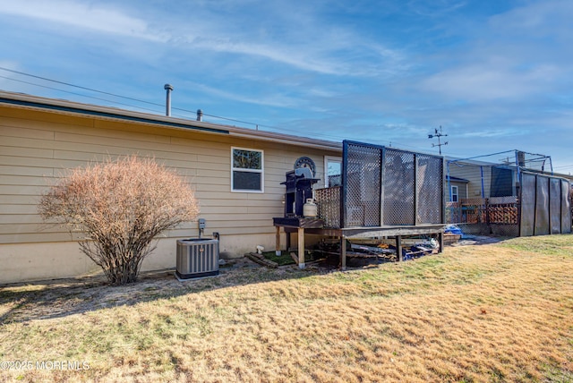 rear view of house with central AC and a lawn