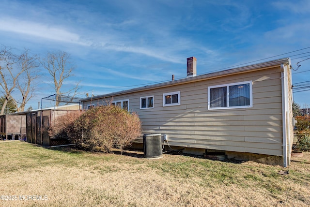 back of house with central AC and a lawn