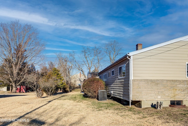 view of side of property with central AC and a lawn