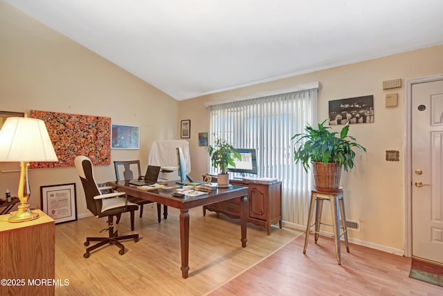 office with light wood-type flooring and lofted ceiling