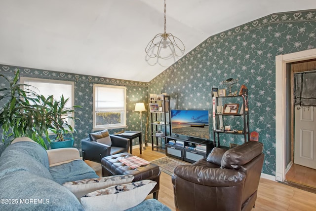 living room featuring light hardwood / wood-style floors, a notable chandelier, and vaulted ceiling