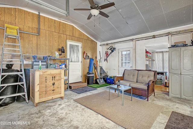 interior space featuring vaulted ceiling, wood walls, and ceiling fan