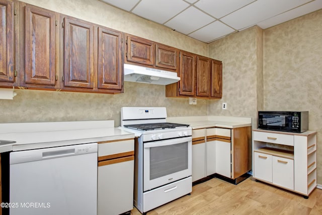 kitchen with a paneled ceiling, white appliances, and light wood-type flooring