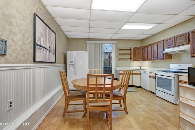 kitchen with a paneled ceiling, white appliances, light wood-type flooring, and sink