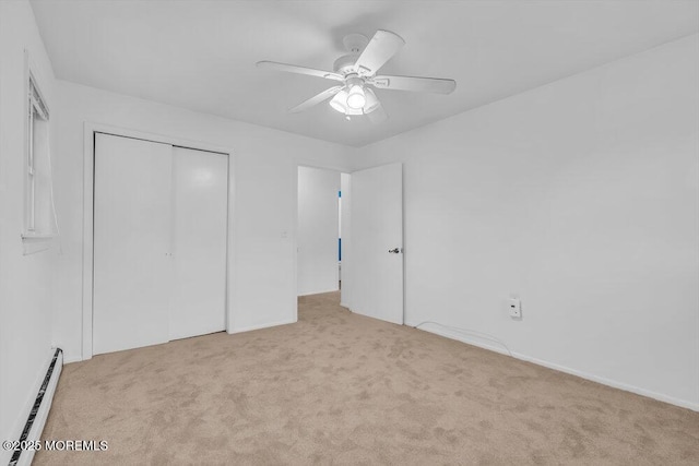 unfurnished bedroom featuring a baseboard heating unit, light colored carpet, ceiling fan, and a closet