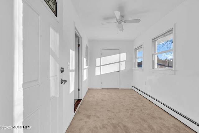 spare room featuring a baseboard heating unit, ceiling fan, and light colored carpet