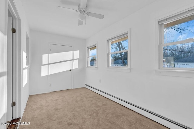 unfurnished room with ceiling fan, light colored carpet, and a baseboard heating unit