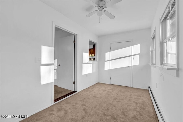 unfurnished room with a baseboard radiator, light carpet, ceiling fan, and a healthy amount of sunlight