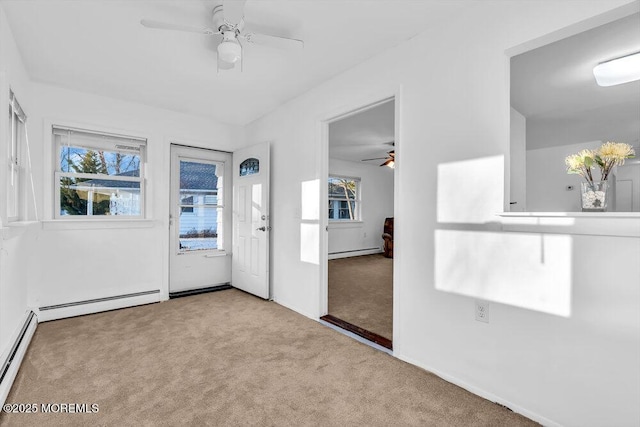 carpeted spare room featuring baseboard heating and ceiling fan