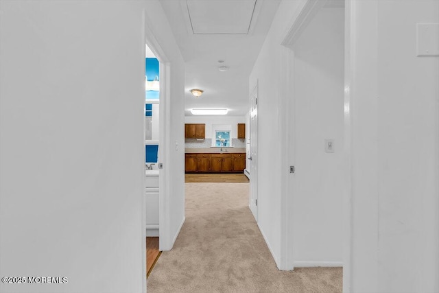 hallway featuring sink and light carpet