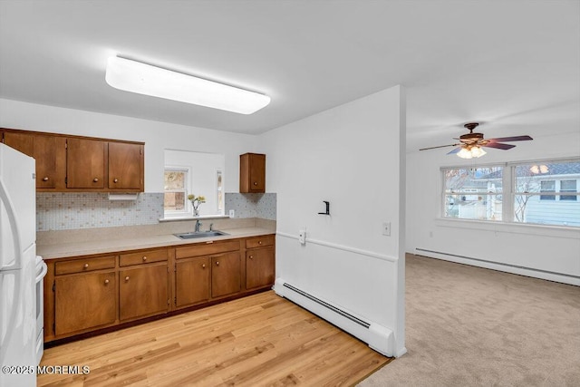 kitchen with white appliances, a baseboard heating unit, ceiling fan, and sink