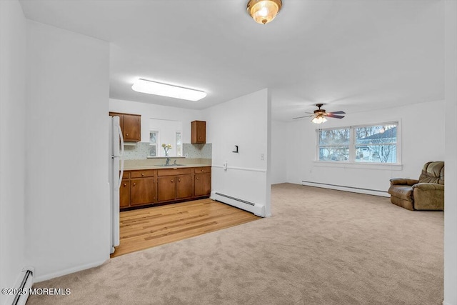 kitchen featuring light carpet, backsplash, and a baseboard heating unit