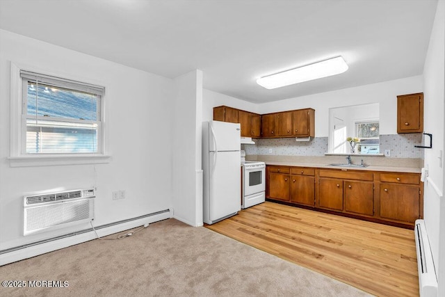 kitchen with white appliances, a wall mounted AC, a baseboard radiator, and sink