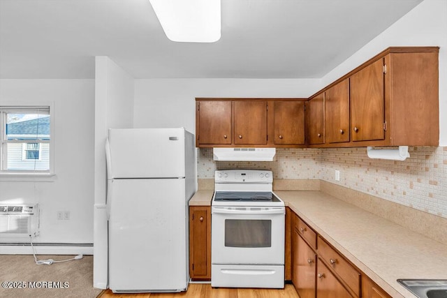 kitchen with an AC wall unit, white appliances, baseboard heating, and tasteful backsplash