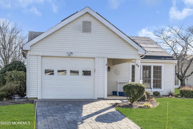 view of front of house with a garage, a front yard, and solar panels