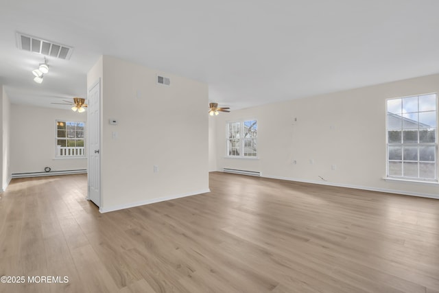 empty room featuring a baseboard heating unit and light hardwood / wood-style floors