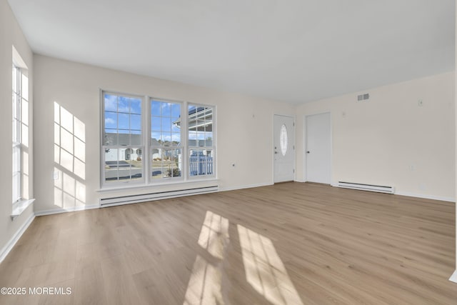 unfurnished living room with light hardwood / wood-style floors, baseboard heating, and plenty of natural light